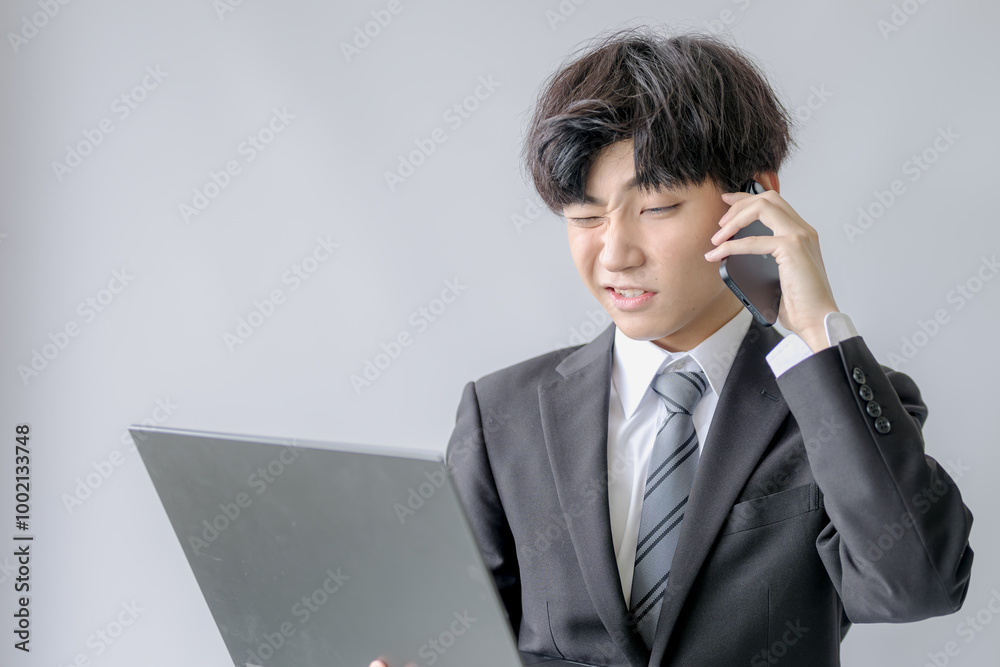 PCとスマホと顔を歪めるビジネスマン PCとスマホと顔を歪めるビジネスマン