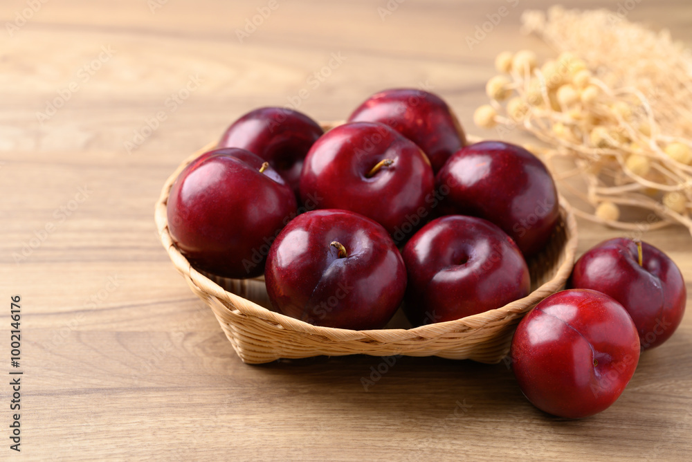 Red plum fruit in basket on wooden background Red plum fruit in basket on wooden background