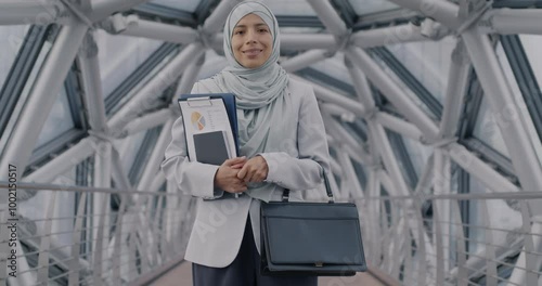 Wallpaper Mural Slow motion portrait of Middle Eastern woman in hijab standing in modern glass hall wearing suit and hijab holding documents and briefcase smiling looking at camera Torontodigital.ca