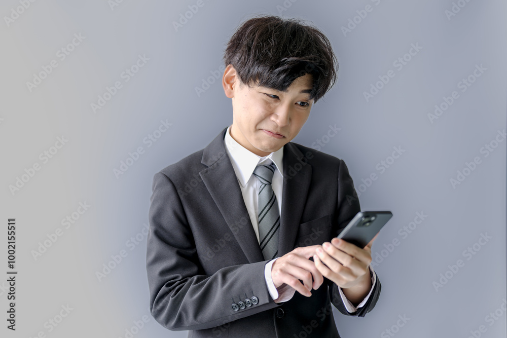 凄い表情でスマホを見る若いスーツ男性 凄い表情でスマホを見る若いスーツ男性