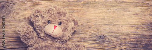 Brown teddy bear over wooden background