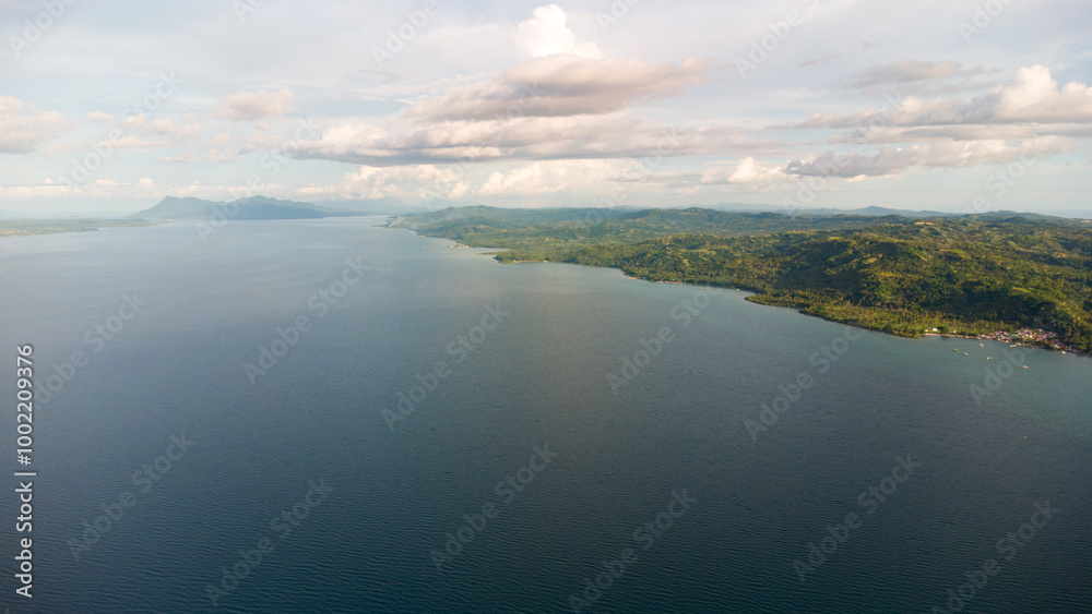 Aerial view of the ocean surface with mountains and clouds in the background Aerial view of the ocean surface with mountains and clouds in the background