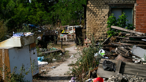 A cluttered backyard with neglected furniture and scattered debris highlights severe poverty and homelessness