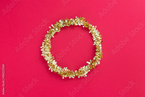 Shiny golden Christmas wreath on red textured background