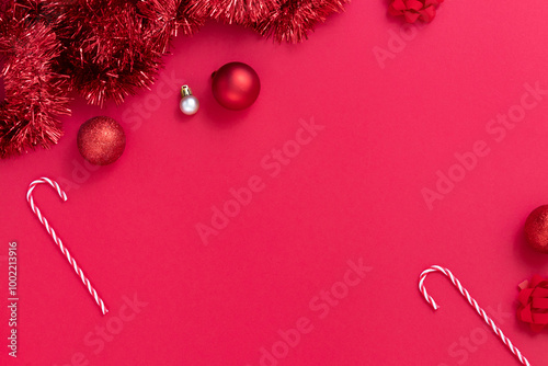 Frame of Christmas ornaments, candy canes, gifts, nutcrackers on red textured background.