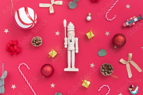 Christmas nutcracker with Christmas ornaments, candy canes, presents, Christmas balls on red background