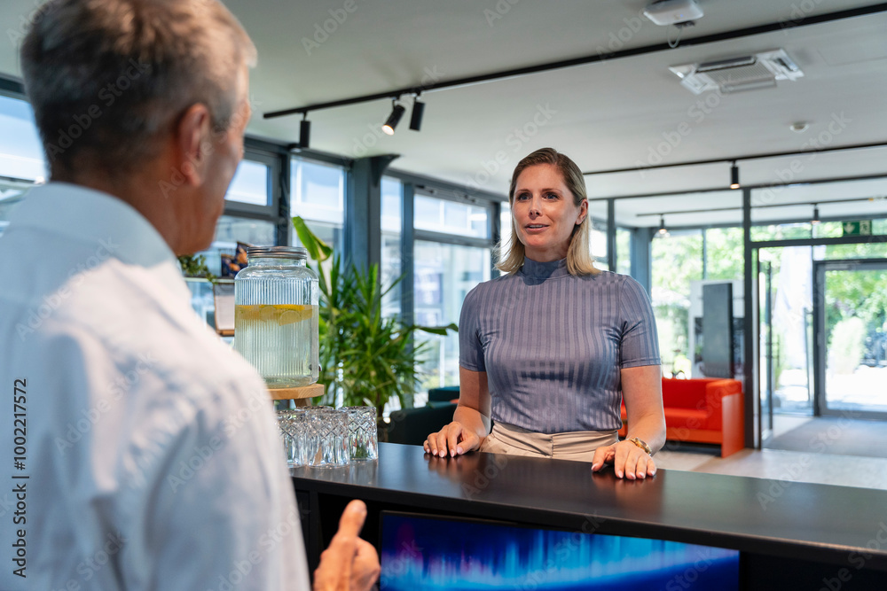 Senior receptionist taking to woman at reception desk in hotel Senior receptionist taking to woman at reception desk in hotel