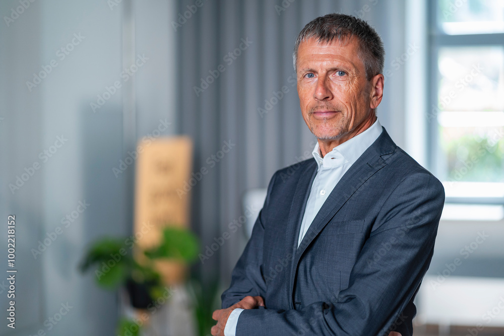 Smiling senior businessman wearing suit and standing in office Smiling senior businessman wearing suit and standing in office