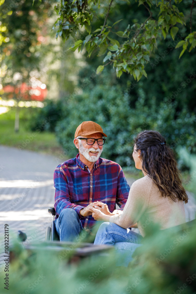 Smiling retired senior man in wheelchair holding hands with caregiver Smiling retired senior man in wheelchair holding hands with caregiver