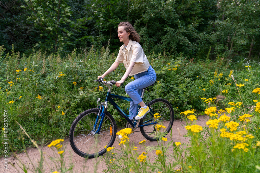 Happy young woman riding bicycle near plants on road Happy young woman riding bicycle near plants on road