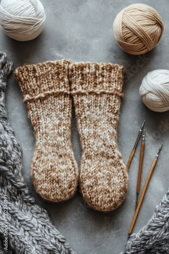 Cozy handmade knit socks with yarn balls and knitting needles on a textured b...