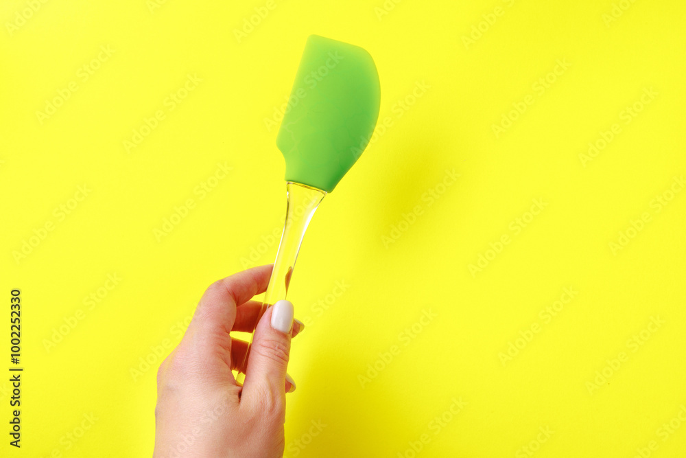 Womans hand holding silicone green spatula with plastic handle on color background- Image Womans hand holding silicone green spatula with plastic handle on color background- Image