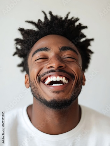 Joyful man with natural hair smiling brightly against a neutral background in...