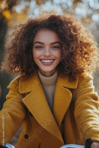 Young woman with curly hair smiles on a bicycle during autumn in the park