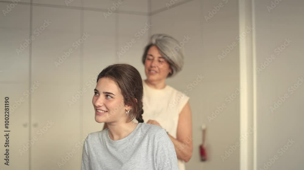 Mother braiding her daughter's hair at home Mother braiding her daughter's hair at home