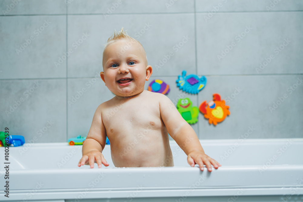 Blond toddler standing in white bathroom and smiling. The child bathes independently. Blond toddler standing in white bathroom and smiling. The child bathes independently.