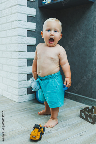 A toddler boy in shorts runs around the apartment at home. The child is playing at home. Active entertainment at home with the child.