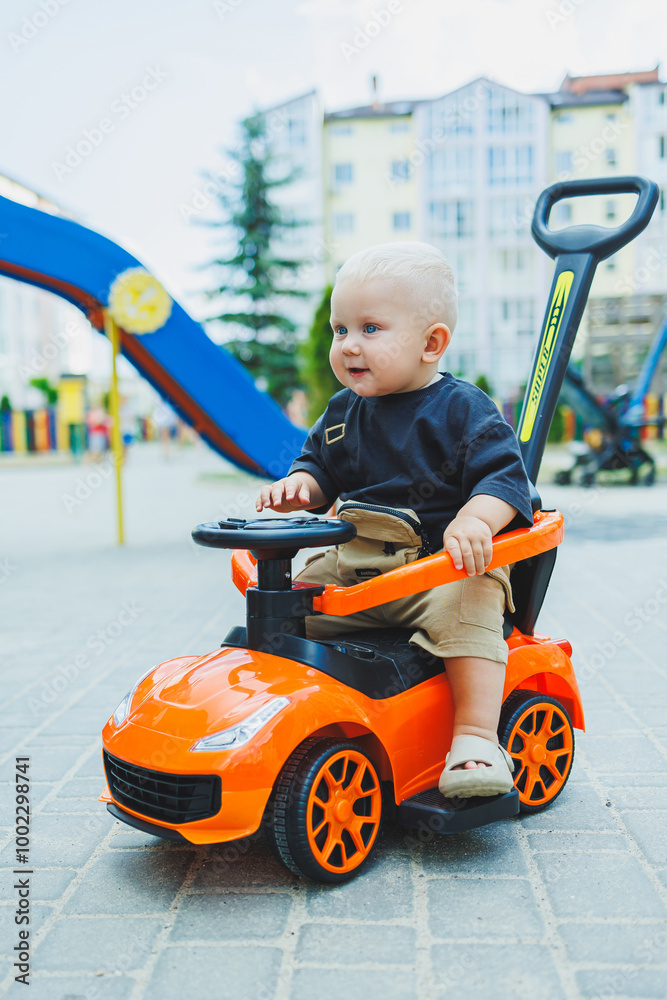 A little boy, 1 year old, sits in a plastic car. A machine for feeding babies. Tolokar for children. A little boy, 1 year old, sits in a plastic car. A machine for feeding babies. Tolokar for children.