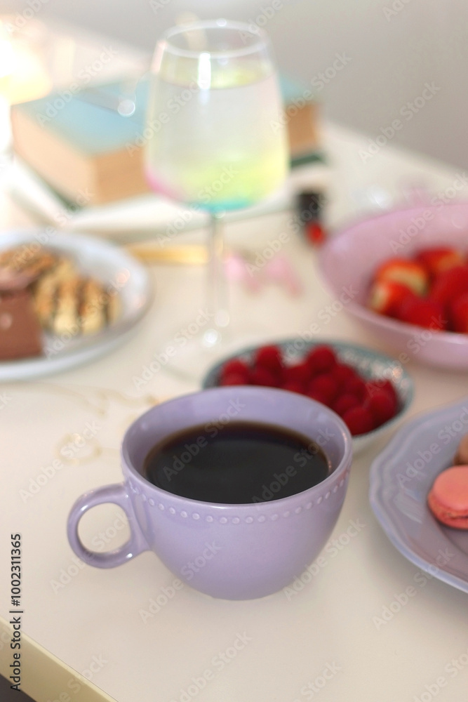Plate of pastel macarons, cookies and chocolate, cup of tea of coffee, glass of bubble water, various berries, books and accessories on the table. Selective focus, pastel colors. Plate of pastel macarons, cookies and chocolate, cup of tea of coffee, glass of bubble water, various berries, books and accessories on the table. Selective focus, pastel colors.