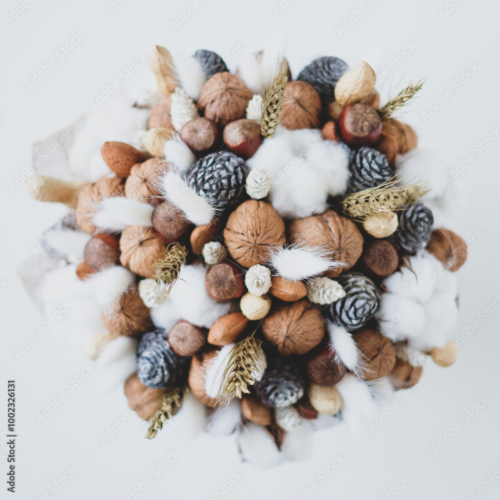 Beautiful handmade Christmas bouquet of nuts, pinecones and cotton flowers, top down view on white background. Holiday floral decor.