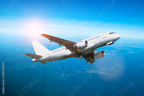 Airplane in the flight, travel background with airplane flying in the blue sky high above the ground. Flying airplane with blank livery