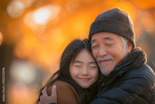 Asian girl hugging her grandfather, smiling and happy, in a park background. Family concept and love for elderly people with copy space.