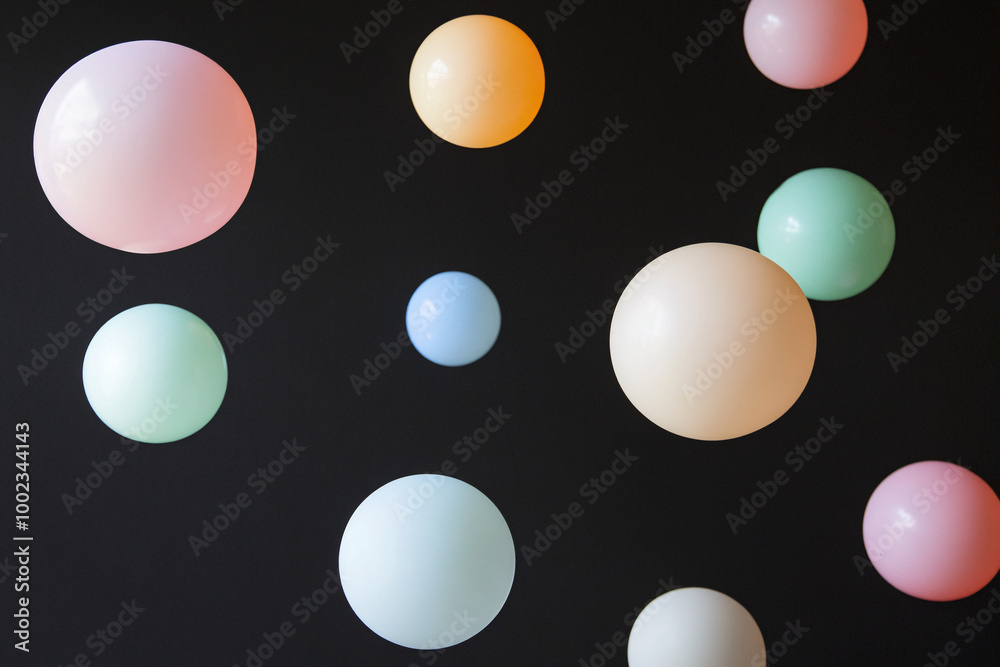 Soft pastel-colored balloons floating against a dark background with a minimalist, airy feel Soft pastel-colored balloons floating against a dark background with a minimalist, airy feel