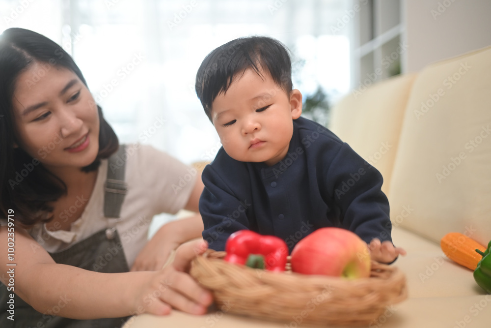 Adorable little baby playing with vegetable toys on sofa at home. Child care concept Adorable little baby playing with vegetable toys on sofa at home. Child care concept