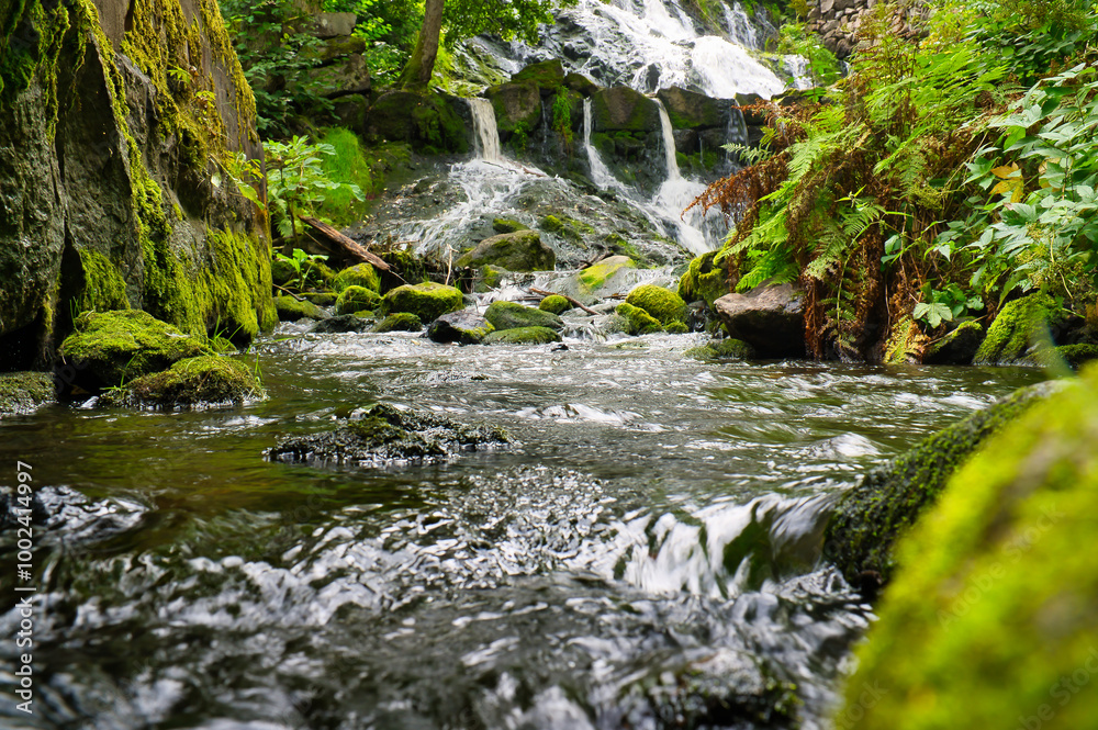 Small waterfall flows into a stream in Sweden. Forest on the riverbank. Small waterfall flows into a stream in Sweden. Forest on the riverbank.