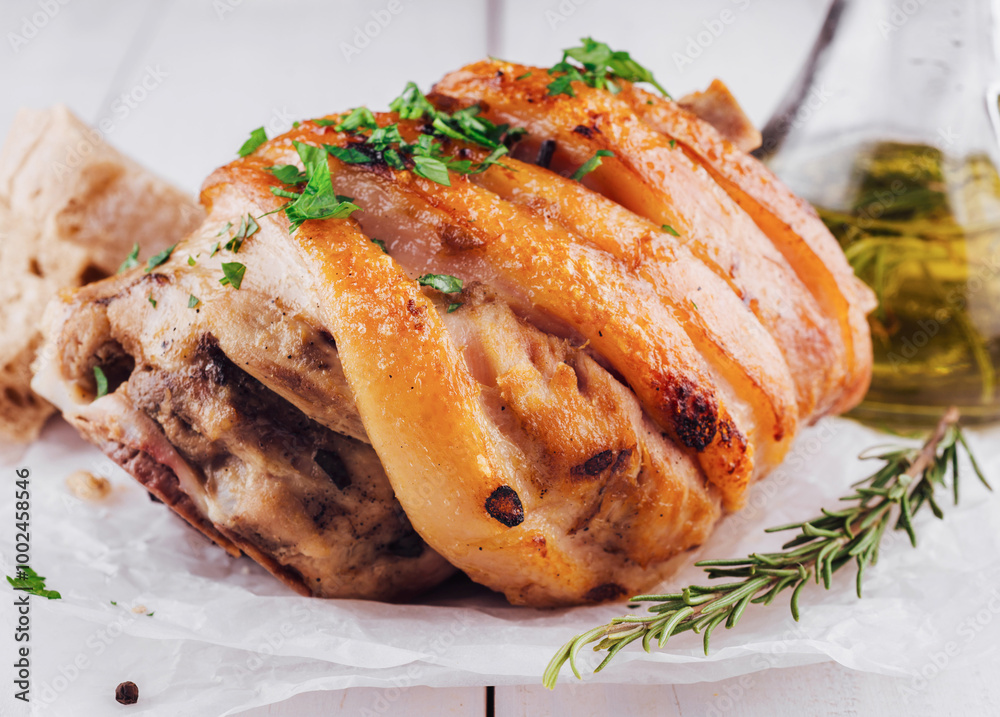 Crispy pork knuckle with rosemary and spices on white table Crispy pork knuckle with rosemary and spices on white table