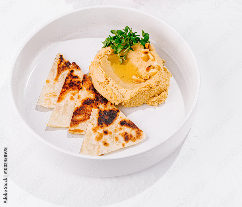 Hummus topped with pine nuts and olive oil served with pita bread and vegetables Hummus topped with pine nuts and olive oil served with pita bread and vegetables