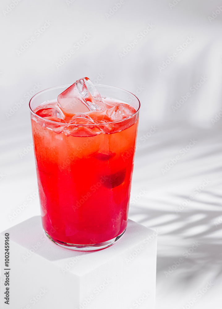 Red cocktail standing on white cube with palm leaf shadow Red cocktail standing on white cube with palm leaf shadow