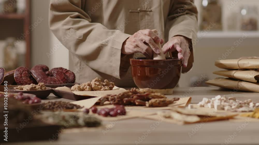 Video template in the setting of a traditional medicine room, cloves are put into a brown mortar by the herbalist and then crushed in a wooden pestle.