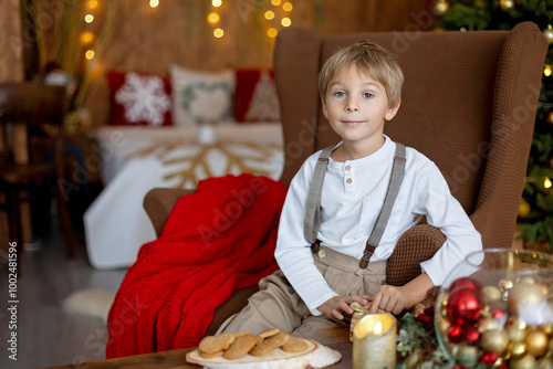 Sweet blond child, cute boy, playing with christmas toys on Christmas, beautifully decorated home for Christmas, cosy place photo