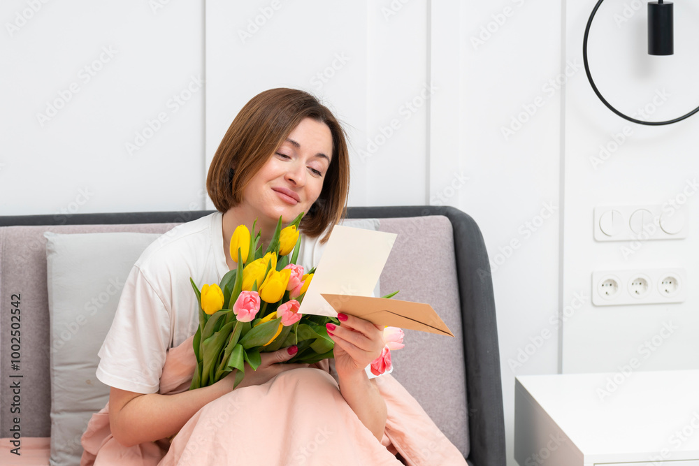 A young beautiful girl received a bouquet of flowers and a congratulatory letter on a wonderful World Women's Day. She sits and reads the letter and thanks the sender A young beautiful girl received a bouquet of flowers and a congratulatory letter on a wonderful World Women's Day. She sits and reads the letter and thanks the sender