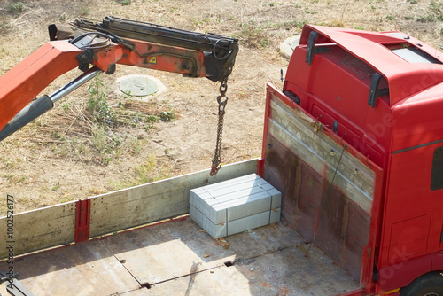 Canvas Print Crane loader preparing to unload concrete guardrails from the back of a truck, c