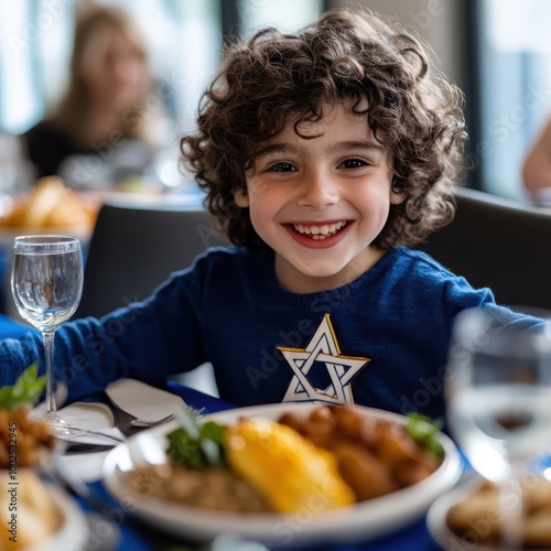 a young boy smiles while sitting at a table with food photo