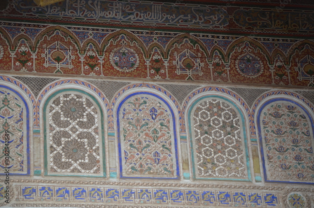 Obraz premium Ornate Moroccan wall with intricate geometric and floral patterns, featuring traditional Islamic calligraphy at the top. The detailed craftsmanship showcases rich cultural heritage in Marrakesh.