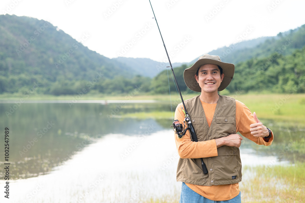Fisherman man fishing with a spinning fishing rod in hand, close-up on the bank of a river or lake. With the light scene during the sunset against the natural forest in the background Hobby,fisherman. Fisherman man fishing with a spinning fishing rod in hand, close-up on the bank of a river or lake. With the light scene during the sunset against the natural forest in the background Hobby,fisherman.