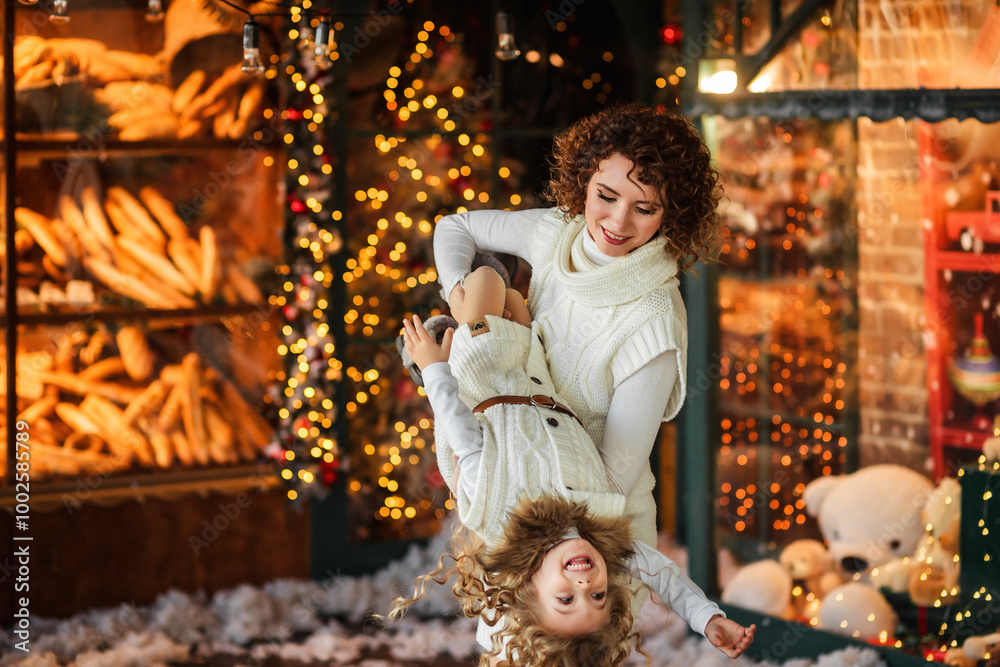 A mother and her daughter are having fun in front of the Christmas trees, decorating with ornaments and decorating for the winter holiday season A mother and her daughter are having fun in front of the Christmas trees, decorating with ornaments and decorating for the winter holiday season