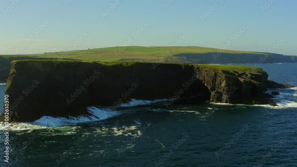 Striking view of an island in the foreground with waves crashing, backed by Kilkee Cliffs. Co. Clare Striking view of an island in the foreground with waves crashing, backed by Kilkee Cliffs. Co. Clare
