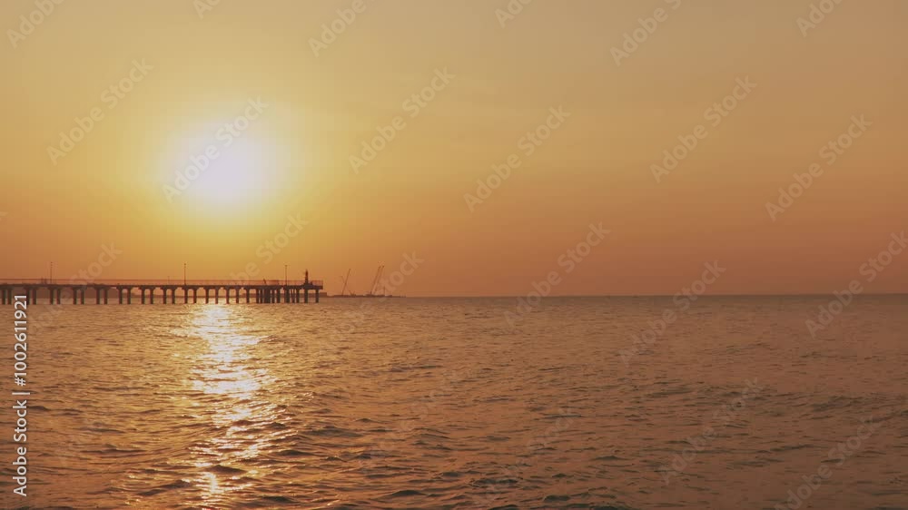 Silhouettes of harbor cranes in a seaport at sunset. Calm sea in the evening light. Empty space for text. Silhouettes of harbor cranes in a seaport at sunset. Calm sea in the evening light. Empty space for text.