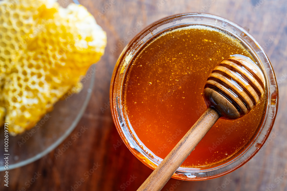 Fresh honey in glass jar with wooden honey dipper, close up, top view Fresh honey in glass jar with wooden honey dipper, close up, top view
