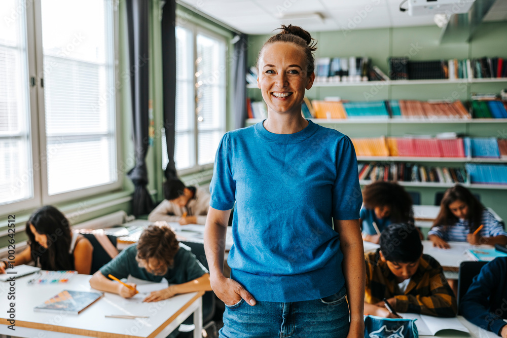 Portrait of happy female professor with hand in pocket standing in classroom at elementary school Portrait of happy female professor with hand in pocket standing in classroom at elementary school