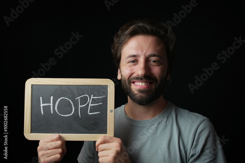 Happy Caucasian Man holding a Chalkboard with the Handwritten word  "Hope"