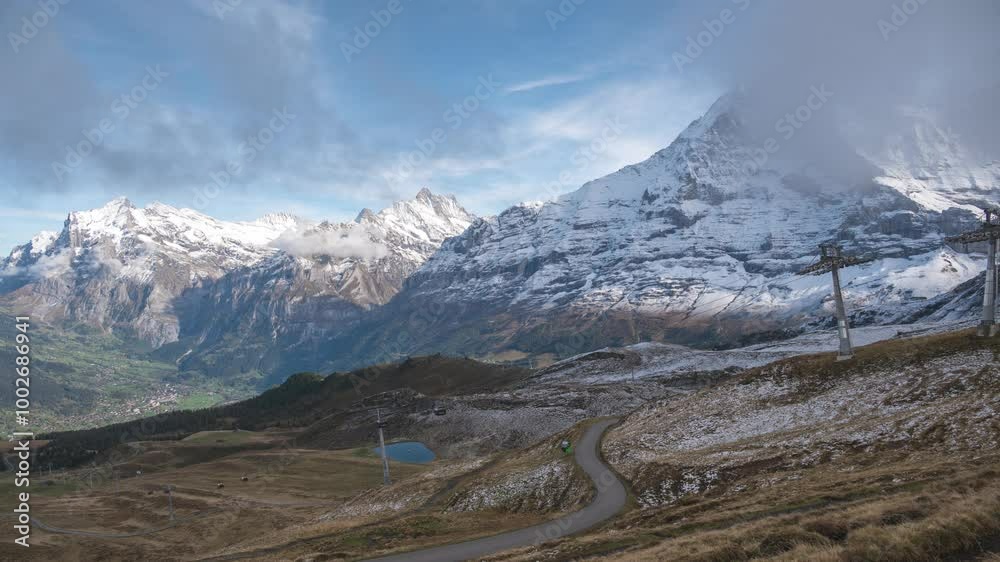 Nature landscape time lapse of Swiss Alps mountain range at Eiger peak and Mannlichen cable car with Grindelwald village Nature landscape time lapse of Swiss Alps mountain range at Eiger peak and Mannlichen cable car with Grindelwald village