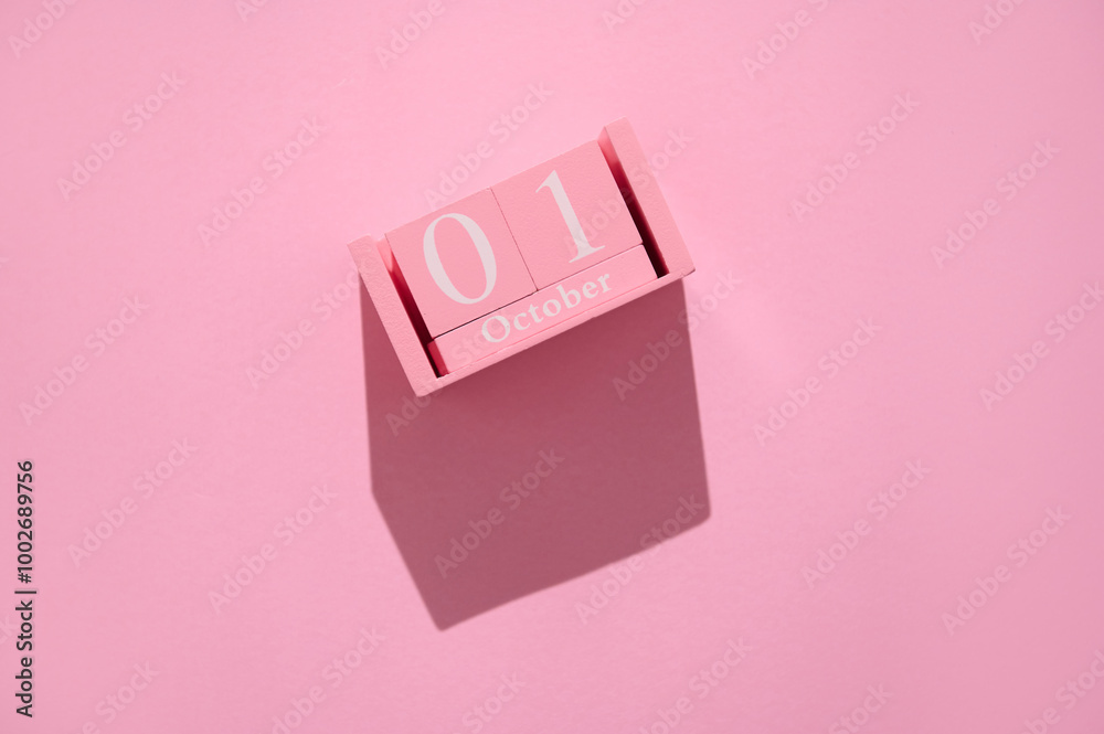 Pink calendar block displaying October 1st against a matching pink background with minimalist style Pink calendar block displaying October 1st against a matching pink background with minimalist style