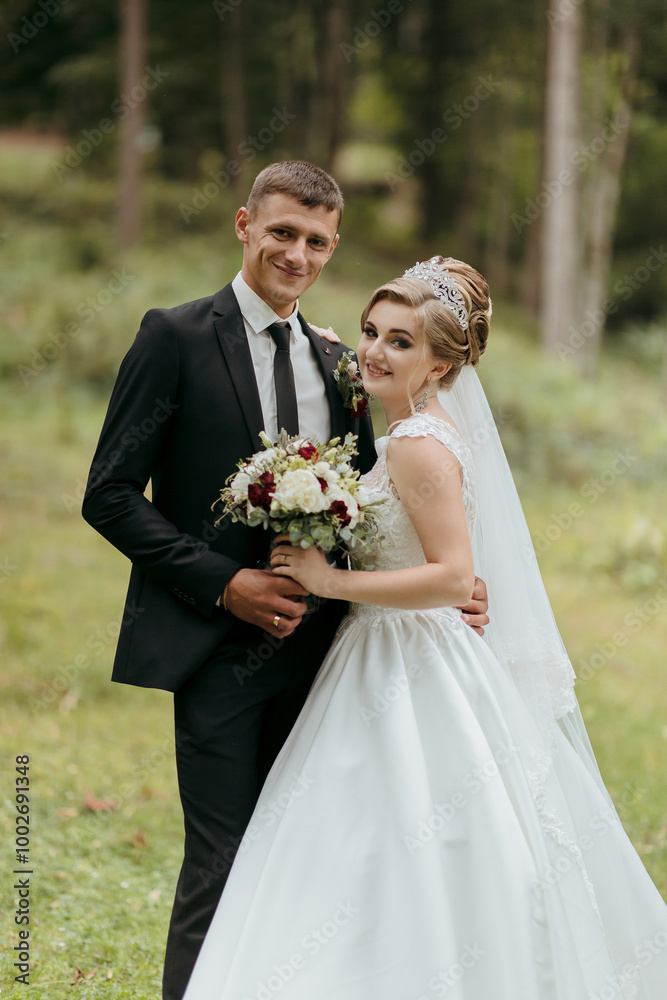 A bride and groom are posing for a picture in a field. The bride is wearing a white dress and the groom is wearing a suit. They are holding a bouquet and a bouquet of flowers A bride and groom are posing for a picture in a field. The bride is wearing a white dress and the groom is wearing a suit. They are holding a bouquet and a bouquet of flowers