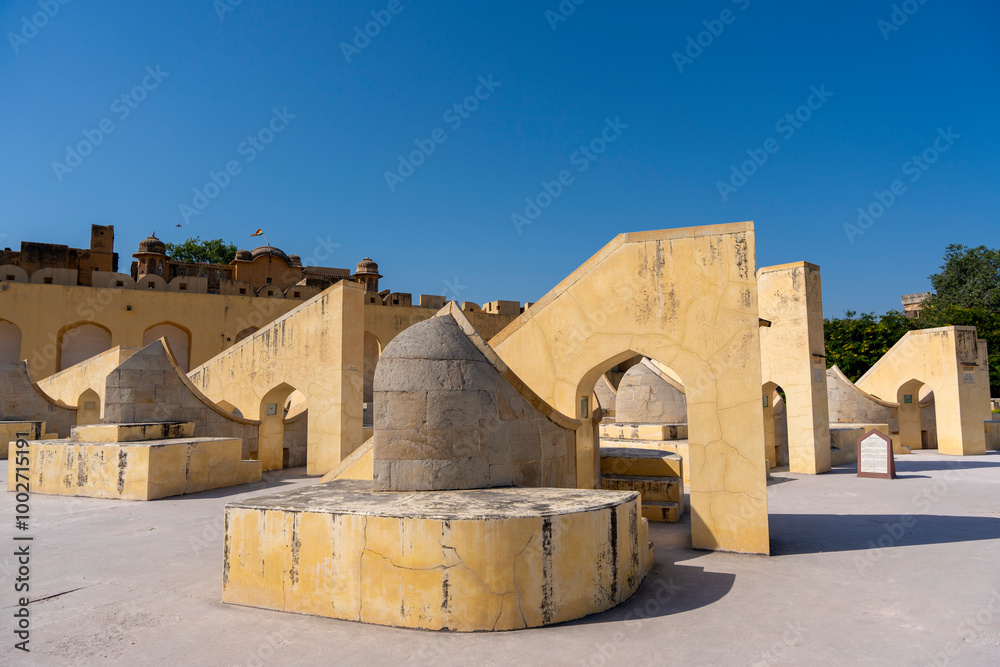 the unique astronomical instruments at Jaipur’s Jantar Mantar observatory. The geometric structures, made of yellow sandstone, feature arches and curves under a bright sunlit sky. the unique astronomical instruments at Jaipur’s Jantar Mantar observatory. The geometric structures, made of yellow sandstone, feature arches and curves under a bright sunlit sky.