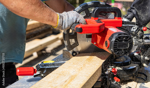 Circular saw cutting a piece of wood. The sawdust created by the saw is flying through the air. Close-up manual circular saw on slides for sawing wood in the home workshop.